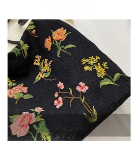 Detailed macro view of colorful floral embroidery on a black knit bucket bag surface