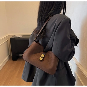 Détail du sac à bandoulière en daim marron vintage avec fermoir doré tournant chic