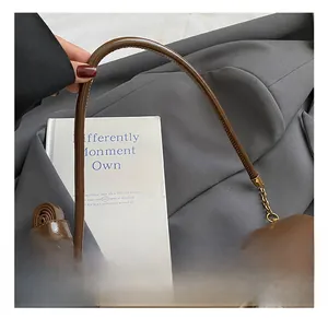 Détail de la poignée en cuir marron vintage et du fermoir doré sur ce sac à bandoulière