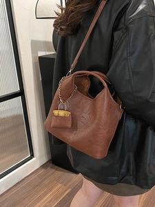Sac seau marron en cuir PU avec mini pochette et chaîne dorée porté par un mannequin