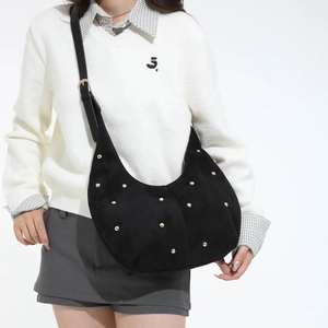 Sac hobo croissant noir avec rivets dorés et bandoulière porté par un mannequin