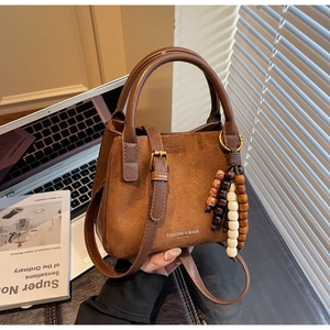 Details der karamellbraunen Wildledertasche mit Ledergriff und Holzperlen-Anhänger