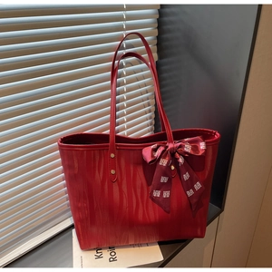 Detailed macro view of red tote bag with wavy leather texture and a ribbon bow decoration