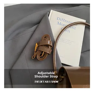 Détail de la bandoulière réglable en similicuir marron avec finitions dorées brillantes