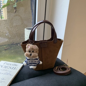 Detail of vintage brown suede bucket bag with leather handles and teddy dog charm