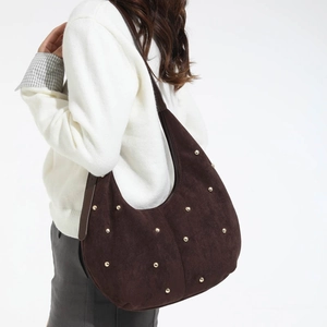 Dettaglio della borsa hobo in camoscio caffè con borchie dorate e texture materica