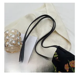 Detailed close-up of floral embroidery on a black shoulder bag with leather straps