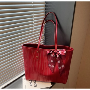 Detail of red tote bag with wave texture and bridal bow scarf on a sunny windowsill
