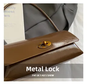 Gros plan du fermoir rotatif ovale doré sur le sac en cuir brillant marron foncé