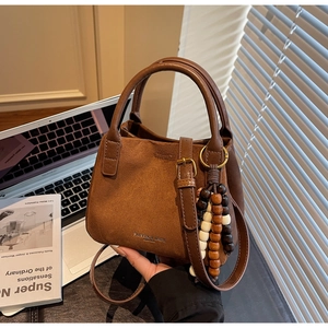 Detailansicht braune Wildledertasche mit Holzperlenanhänger und Bronze-Hardware
