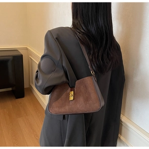 Vue détaillée du sac porté épaule en daim marron avec fermoir tournant doré sur modèle