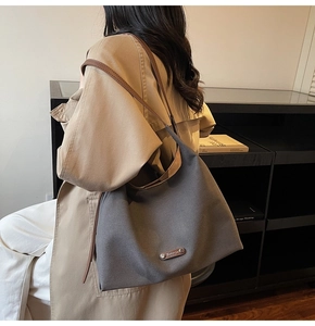Detail of charcoal canvas tote bag with brown leather straps worn by model for daily commute