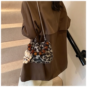 Detail of leopard plush bag featuring acrylic beaded handle and silver chain strap