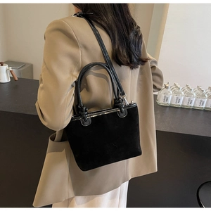 Detail of black suede tote bag with embossed camellia and glossy patent leather straps