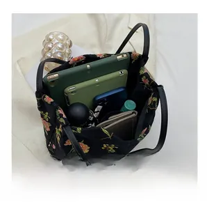 Spacious interior of black canvas bucket bag with floral embroidery and daily essentials