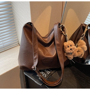 Detailed texture of brown wrinkled leather tote bag with plush dog charm accessory