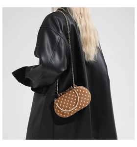 Polka dot handbag detail featuring brown suede material and elegant gold chain strap