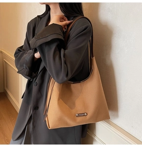 Close-up of camel canvas tote bag with metal nameplate on grey blazer outfit