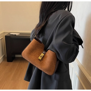 Détail du sac seau marron mat en daim avec boucle dorée et design de bord incurvé élégant