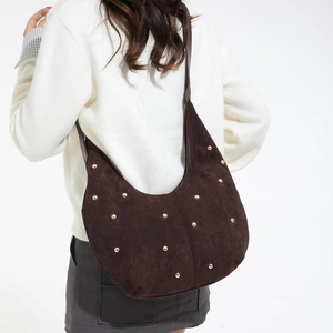 Dettaglio borsa hobo in pelle scamosciata marrone con borchie dorate sulla spalla
