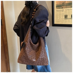 Dettaglio della borsa tote leopardata con tracolla in legno e scritte del logo