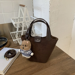 Brown suede tote bag detail with teddy bear pendant and dark leather handles