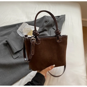 Detailed macro of dark brown suede bucket bag featuring knotted handle and petal logo
