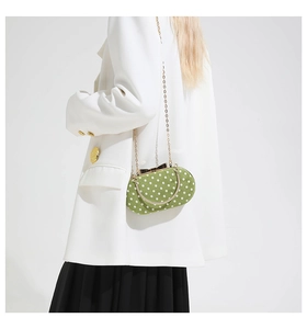 Detail of grass green polka dot bag with gold chain strap and bow-shaped clasp