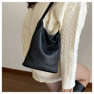 Close-up of black litchi grain bucket bag with U-shaped stitching and long shoulder strap
