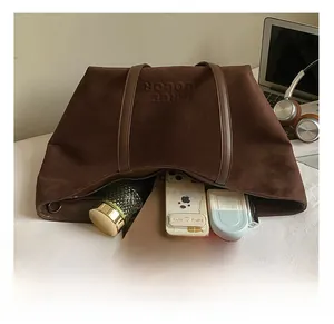 Macro view of large brown suede tote bag showing spacious interior with tablet and items