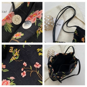 Detail of floral embroidery on black canvas bucket bag with magnetic silver clasp