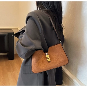 Détail du sac seau en daim marron caramel avec fermoir tournant doré et découpe élégante