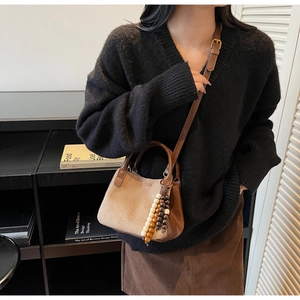 Detail der braunen Eimertasche mit Wildledereinsatz und Holzperlen-Quastenanhänger