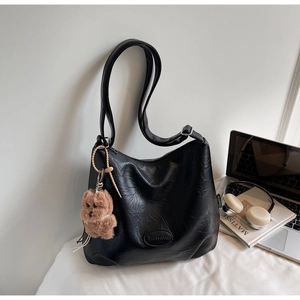 Detail of black large capacity PU leather shoulder bag with a teddy bear charm and logo