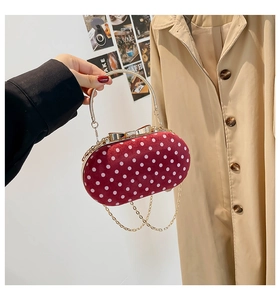 Detailed view of red polka dot handbag with gold ring handle and bow clasp detail