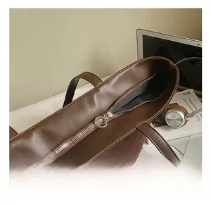 Detail of silver circular zipper on a brown leather tote bag with premium stitching