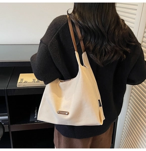 Close-up of minimalist cream canvas tote bag with brown leather shoulder straps