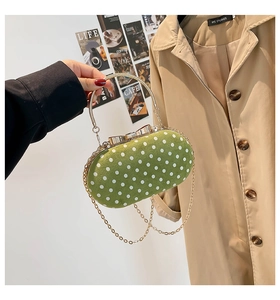 Detail of green polka dot handbag with gold circular metal handle and chain strap