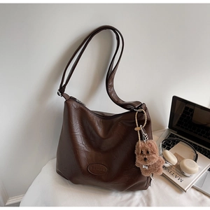Detail of dark brown vintage hobo bag with plush bear charm and Ranatu logo embossing
