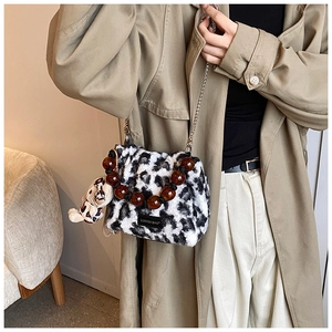Detail of leopard print plush bucket bag with amber bead handle and metal chain