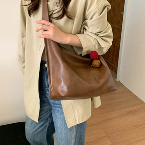 Detail of a brown large-capacity crossbody tote bag with soft PU leather texture