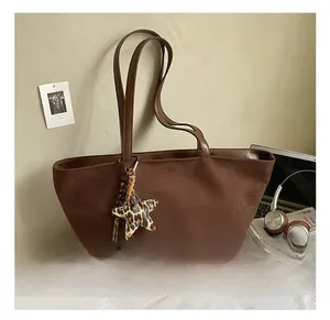 Detail showing brown suede tote bag with leopard star pendant and slim shoulder straps