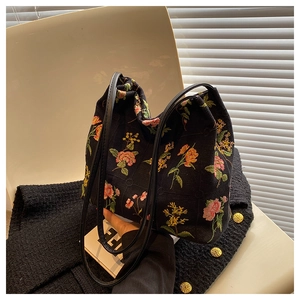 Close-up of black canvas bucket bag with colorful floral embroidery and gold buttons