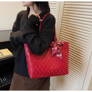 Detail of red tote bag with diamond quilting and festive silk ribbon on shoulder strap