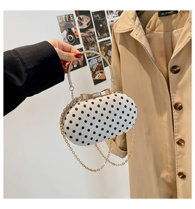 Detailed close-up of a stylish polka dot handbag with elegant golden metal ring handle