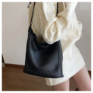 Detail view of black litchi pattern hobo bag worn by a model on the shoulder