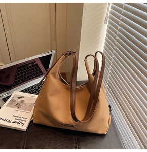 Detail of a large brown canvas tote bag with leather handles on a minimalist desk