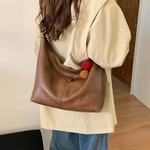 Detailed view of large brown vintage leather tote bag with plush colorful charms