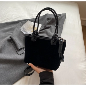 Detail of premium black velvet bucket bag with rope handles on a minimalist background
