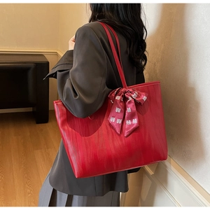 Detail of red textured leather tote bag with silk bow featuring traditional Chinese character